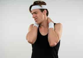 Free photo unpleased young sporty guy with closed eyes wearing headband and wristband grabbed neck isolated on white