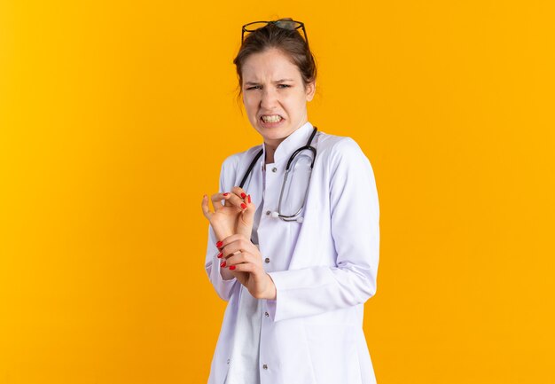 Unpleased young woman in doctor uniform with stethoscope looking down