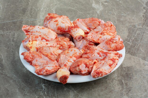 Unprepared chicken legs with spices on white plate. High quality photo