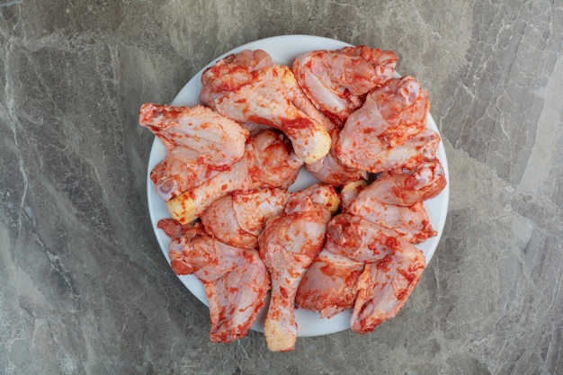 Unprepared chicken legs with spices on white plate. High quality photo