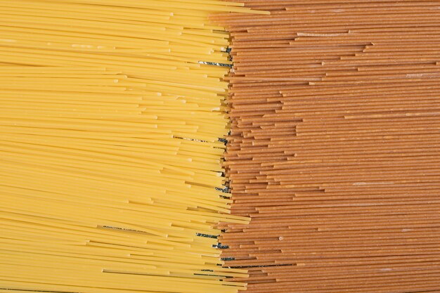 Неподготовленные свежие коричневые и желтые макароны на мраморном фоне. Фото высокого качества