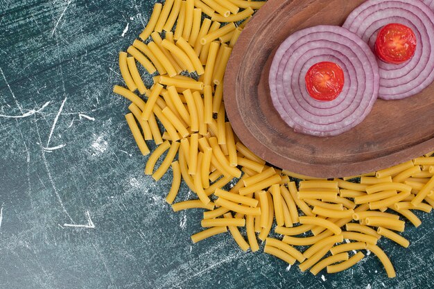 Unprepared fresh macaroni with slices of onion and tomato cherry. High quality photo