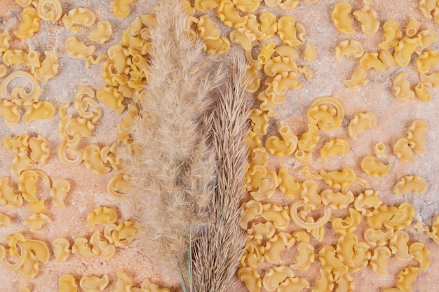 Maccheroni impreparati con grano su fondo di marmo. foto di alta qualità