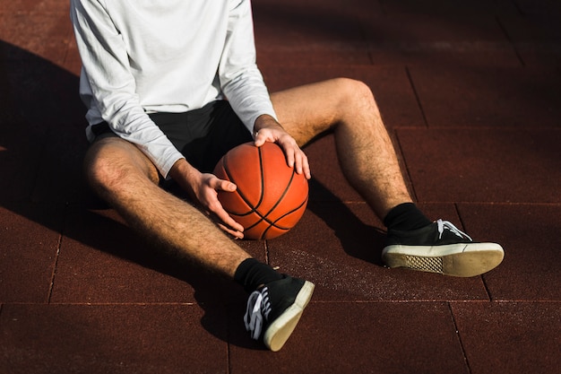 Free photo unrecognisable basketball player relaxing on court