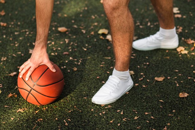 Unrecognisable man playing basketball in nature