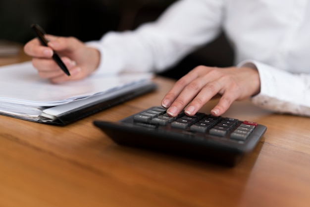 Unrecognisable professional worker typing on calculator