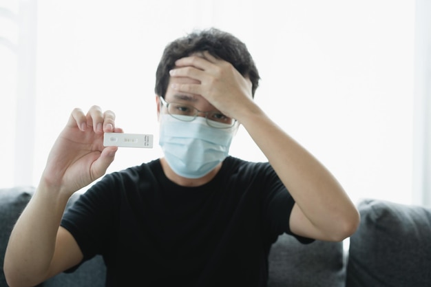 検疫中​に​自宅​で​covid​-​19​または​2019​sars​-​ncov​抗原​迅速​自己​検査​を​使用した​フェイス​マスク​を​持った​認識​できない​アジア​の​若い​男性​、​ag​検査​結果​は​陽性​を​示しました​。