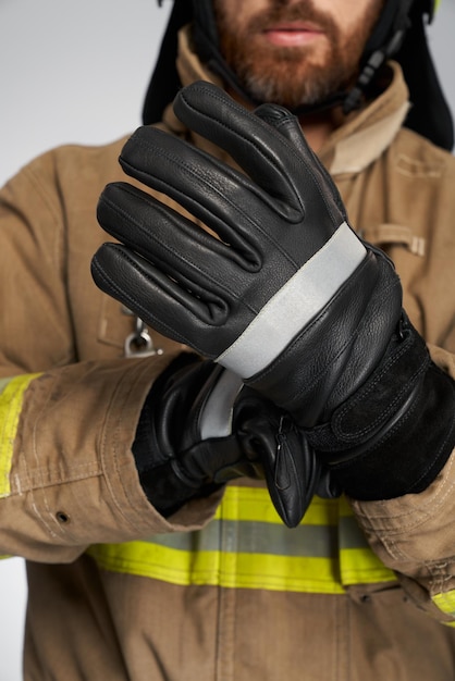 Pompiere barbuto irriconoscibile che indossa guanti protettivi in pelle