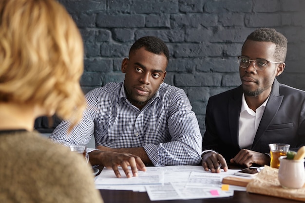 Unrecognizable Caucasian female being interviewed by doubtful future boss and HR director