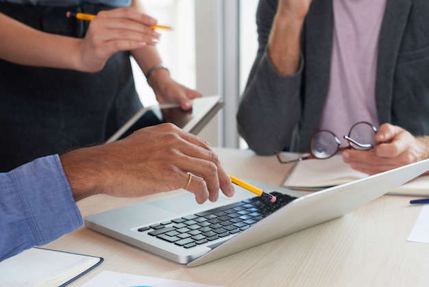 Unrecognizable colleagues looking at laptop screen at work meeting