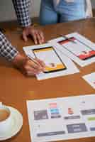 Free photo unrecognizable colleagues standing at table and looking at design projects