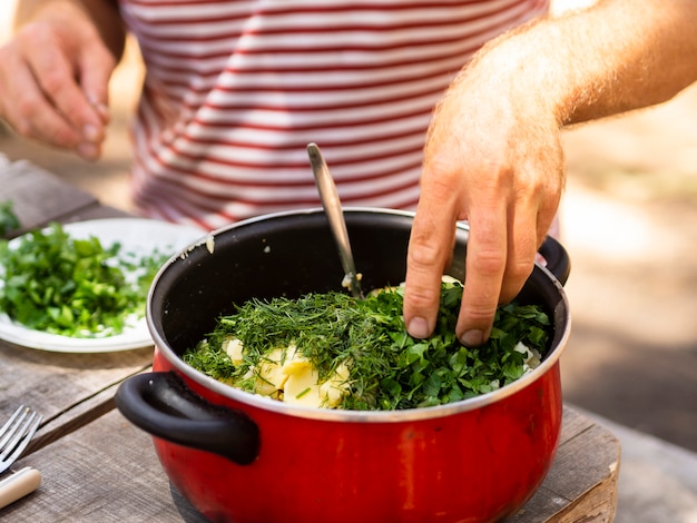 Free photo unrecognizable cook sprinkling boiled potatoes with chopped parsley