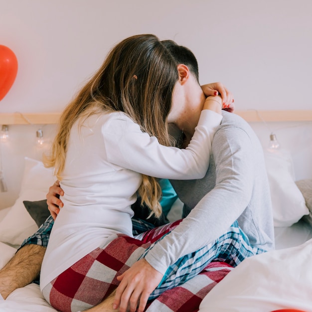 Unrecognizable couple kissing on bed