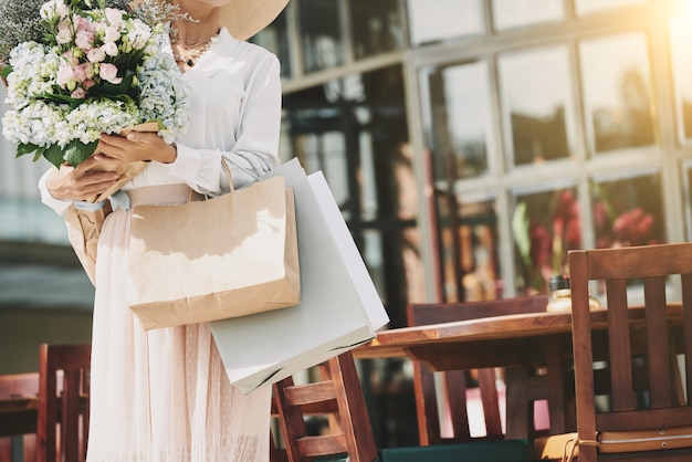 Free photo unrecognizable elegant woman standing near street cafe with flower bouquet