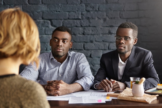 Free photo unrecognizable female candidate with short hair is interviewed by two attractive businessmen