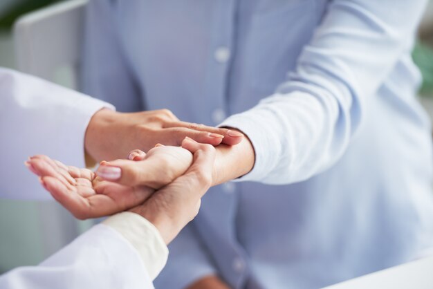 Unrecognizable female doctor checking woman's heart rate