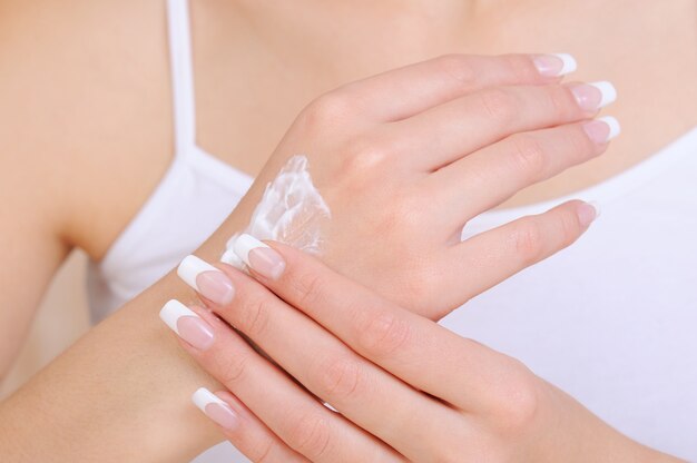 手に化粧品保湿クリームを塗っている認識できない女性