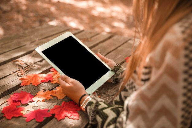 가을 공원에서 태블릿을 사용하여 인식 할 수없는 여성