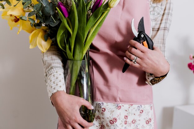 Unrecognizable florist with pruner and flowers