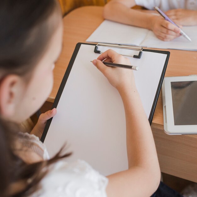 Unrecognizable girl drawing on clipboard