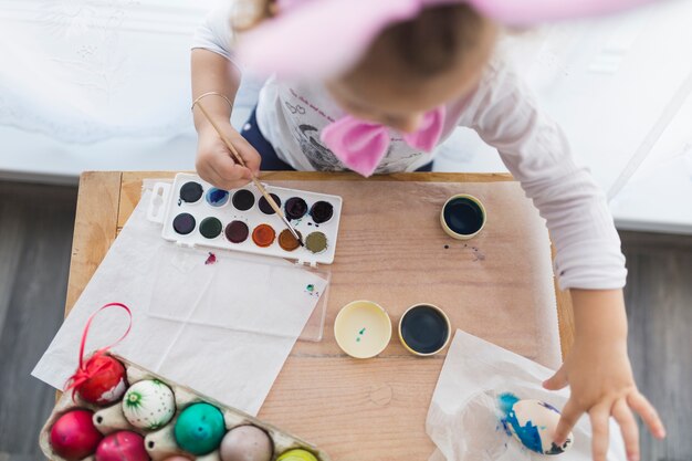 Unrecognizable girl painting eggs