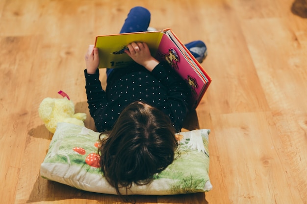 Foto gratuita ragazza irriconoscibile che legge il libro del giocattolo