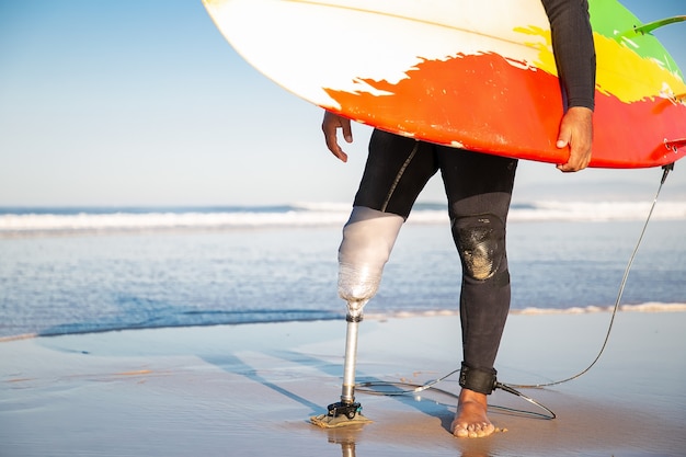 바다 해변에서 서핑 보드와 함께 서있는 인식 할 수없는 남성 서퍼