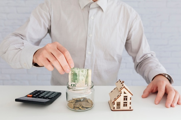 Unrecognizable man putting money to jar