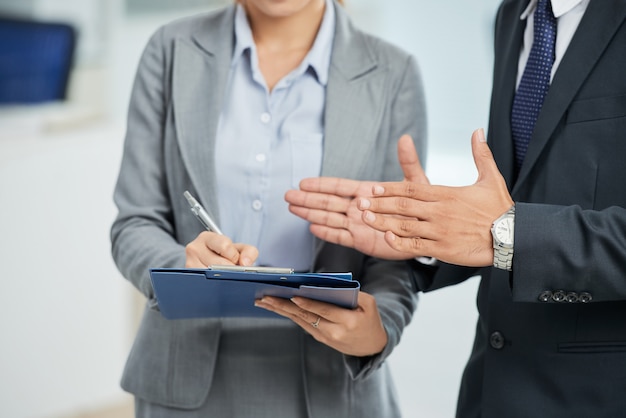 Unrecognizable man in suit gesturing and woman taking notes