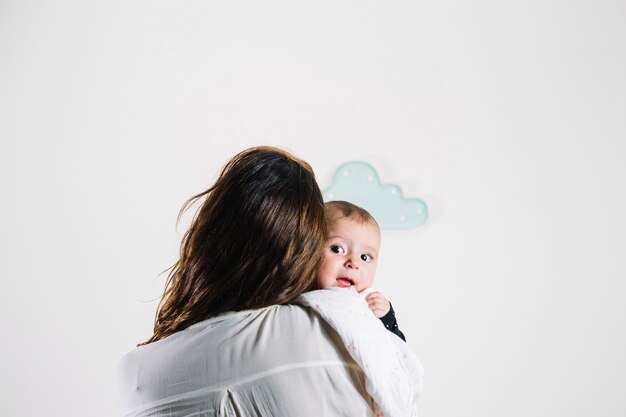 Unrecognizable mother embracing charming baby