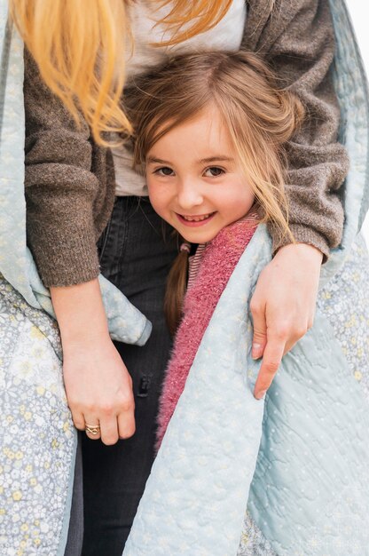 Unrecognizable mother embracing cute daughter