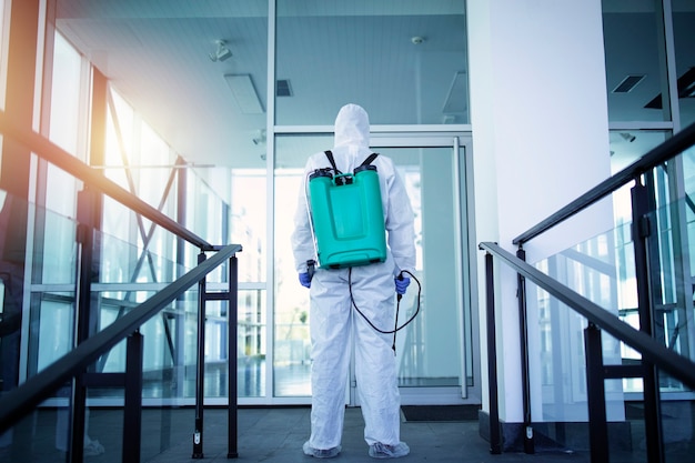 白い保護服を着た認識できない人が、公共エリアを消毒して、伝染性の高いコロナウイルスの拡散を阻止します。