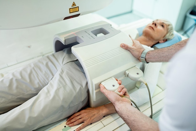 病院で腹部MRIスキャン手順のために女性患者を準備している認識できない放射線科医