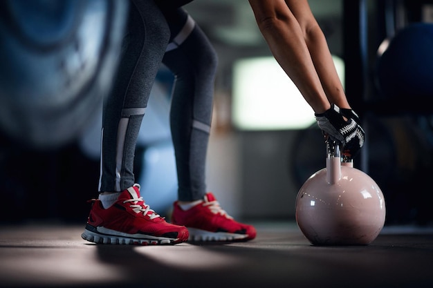 Unrecognizable sportswoman practicing with kettle bell on cross training in fitness center