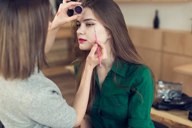 Free photo unrecognizable stylist using eyeliner on model