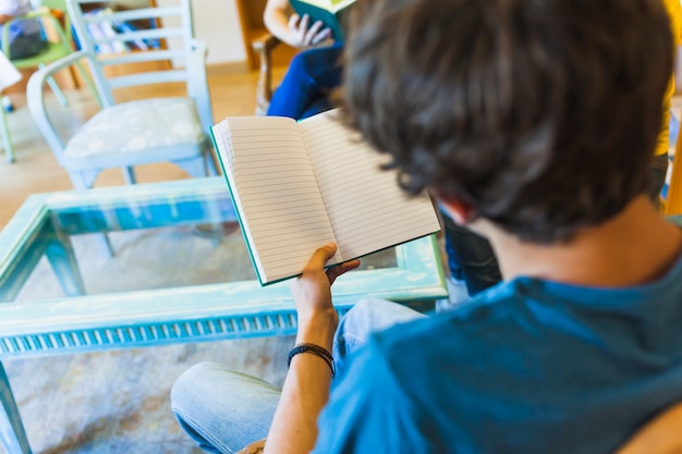 Foto gratuita adolescente irriconoscibile che legge nella biblioteca