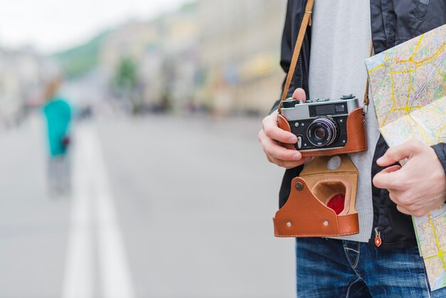 Unrecognizable tourist with camera and map