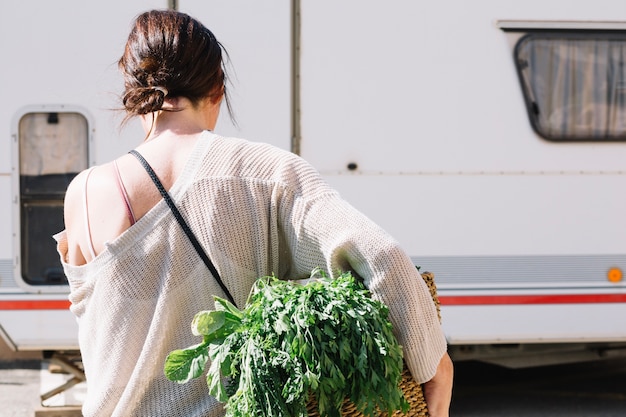 Unrecognizable woman carrying basket with vegetables