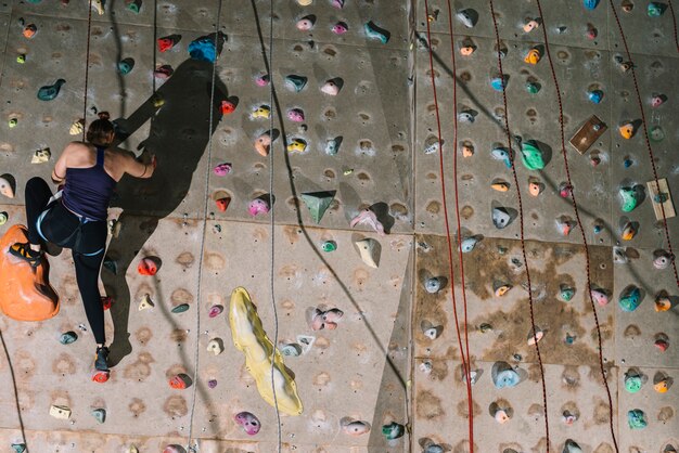 Unrecognizable woman climbing wall