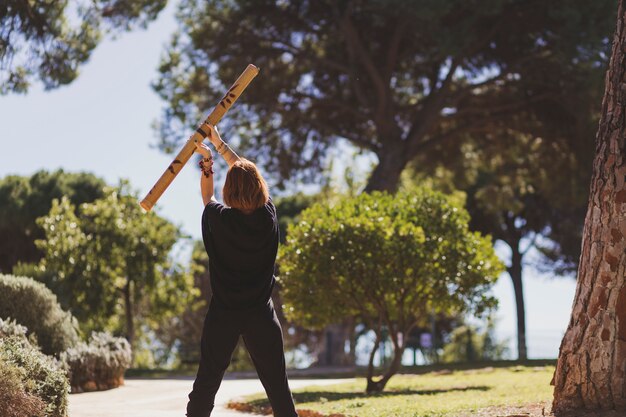 Unrecognizable woman doing exercises with bamboo stick