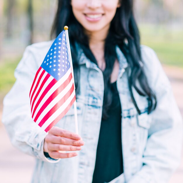 Unrecognizable woman holding American flag during celebration of Fourth of July