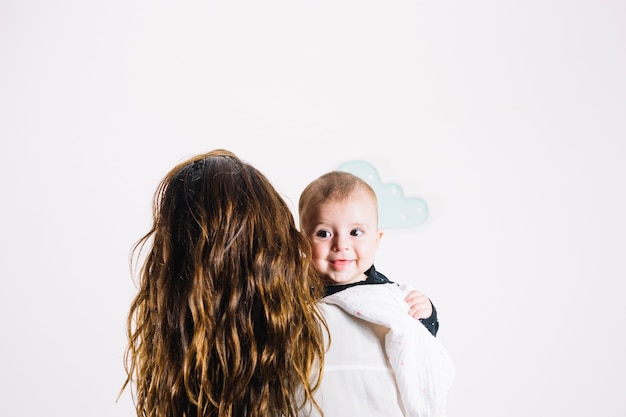 Unrecognizable woman hugging smiling baby