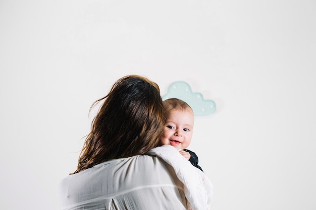 Unrecognizable woman hugging smiling baby