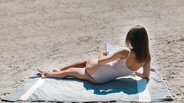 Unrecognizable woman reading on beach