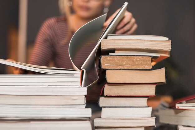 Unrecognizable woman reading book from stack