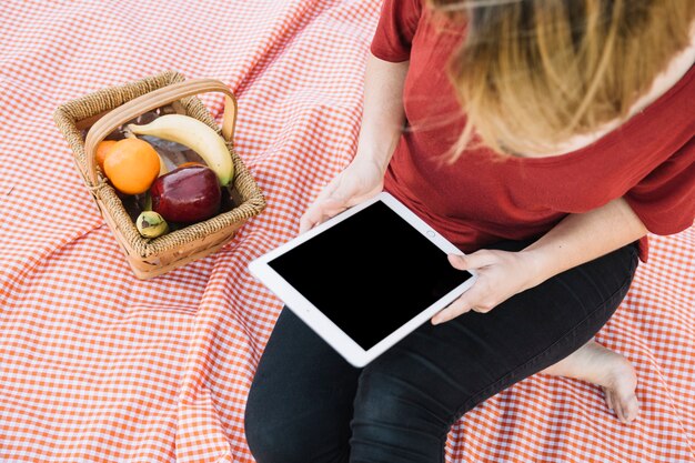 ピクニックでタブレットを使用している認識できない女性