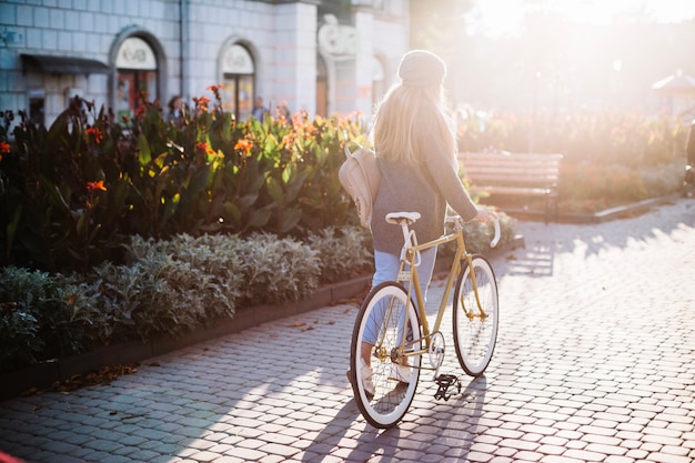 Нераспознаваемая женщина, идущая с велосипедом в парке