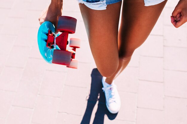 인식 할 수없는 여자 스케이트 보드와 함께 산책