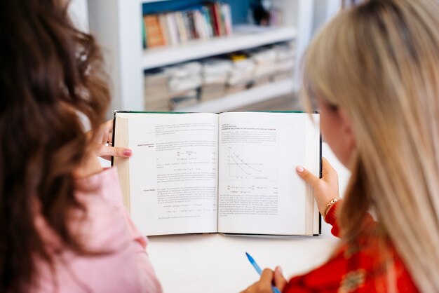 unrecognizable women reading textbook