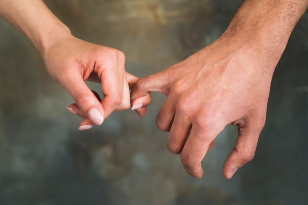 Unrecognizable young lovers holding little fingers